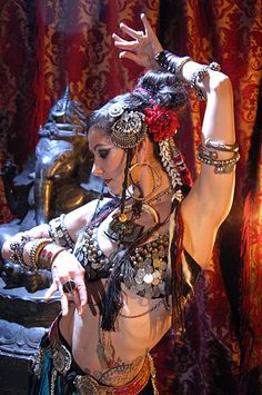 a belly dancer is posing in front of a mirror with her arms stretched out to the side