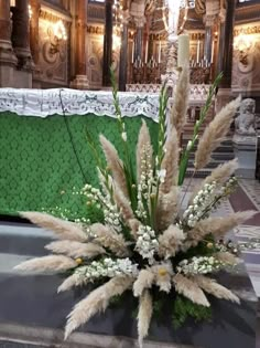 a vase filled with lots of white flowers on top of a table next to a wall