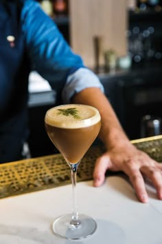 a person sitting at a bar with a drink in front of him and his hand on the counter