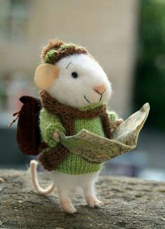 a stuffed animal mouse holding a piece of paper and wearing a green knitted sweater