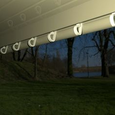 some lights are hanging from the outside of a building in front of trees and water