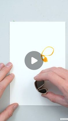 two hands holding up a piece of paper with an orange design on it and the video below