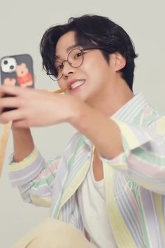 a young man taking a selfie with his cell phone while sitting on the floor