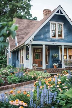 a blue house with lots of flowers in the front yard