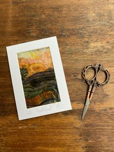 a pair of scissors sitting on top of a wooden table next to a small card