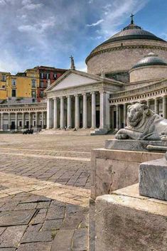 a stone lion statue sitting in front of a building with columns and pillars on either side