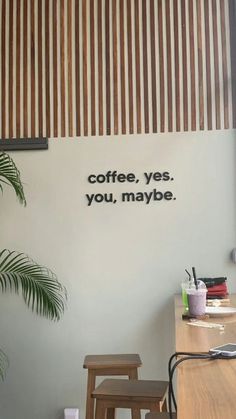 there is a coffee sign on the wall next to two stools and a potted plant