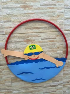 a paper cut out of a boy swimming in the water on a circle with a red handle