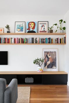 a living room with bookshelves and pictures on the wall above it, along with two couches