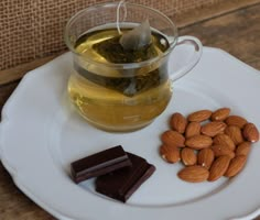 a cup of tea and some almonds on a plate