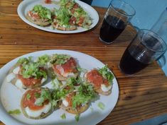 two white plates with food on them next to some drinks