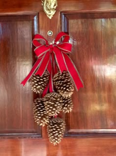 pine cones are tied to a door with a red bow