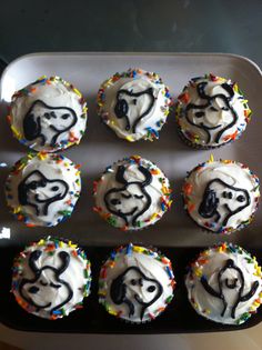 twelve decorated cupcakes with icing and sprinkles on a tray