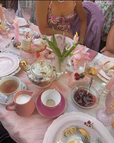 a woman sitting at a table with tea cups and plates