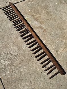 a long wooden comb sitting on top of a cement floor next to a sidewalk with no one around it