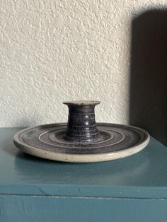 a black and white vase sitting on top of a blue table next to a wall