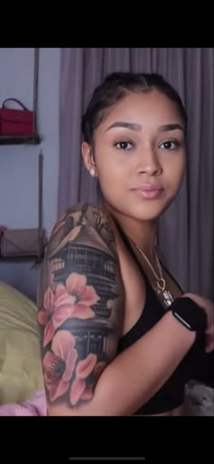 a woman with tattoos on her arm and chest posing for a photo in front of a bed