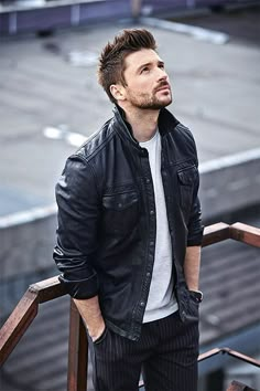 a man in black jacket and white t - shirt standing on stairs