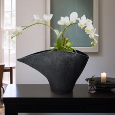 a black vase with white flowers on a table