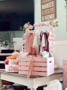 a white table topped with pink boxes filled with baby clothes and other items on top of it