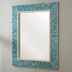 a mirror that is on the wall with a blue and green mosaic pattern around it