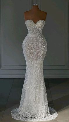 a white wedding dress on a mannequin in front of a gray wall and floor