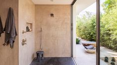 a bathroom with a walk in shower next to a glass door and window overlooking the outdoors