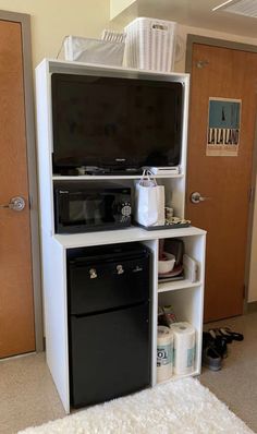 a microwave oven sitting on top of a white shelf next to a door and rug