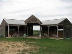 an old barn with two stalls and chairs on the grass in front of it,