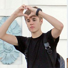 a young man holding his hands up to his head while standing in front of a building