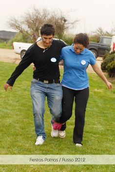 a man and woman are walking in the grass with a frisbee behind them