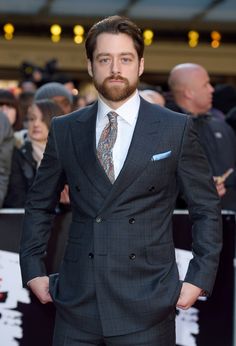 a man in a suit and tie standing on a red carpet