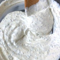 a bowl filled with white sauce and a wooden spoon sticking out of the dip in it