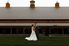 a bride and groom standing in front of a barn