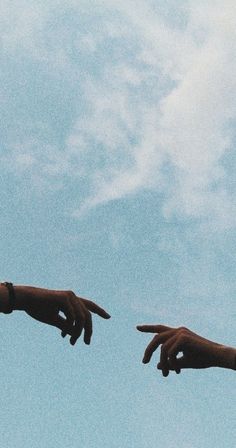 two hands reaching towards each other in the sky