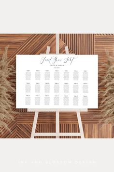 a wedding seating chart on a wooden wall with pamy grass in the foreground