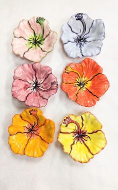 four flower shaped dishes sitting on top of a white table