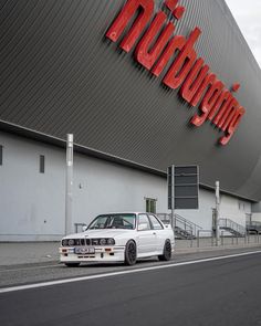 a white car parked in front of a building with a large red sign on it's side