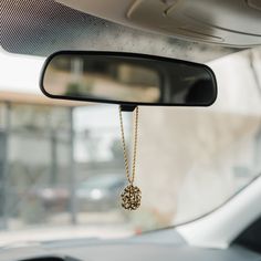 the rear view mirror of a car with a gold chain hanging from it's side