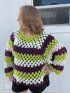 a woman standing in front of a door wearing a crocheted sweater and shorts