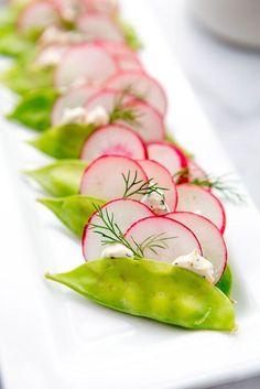 radishes and cucumbers are arranged on a long white plate