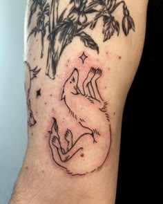 a tattoo on the leg of a man with a wolf and tree in the background