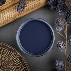 a blue paint in a bowl next to some pine cones