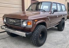 a brown toyota pickup truck parked in front of a garage