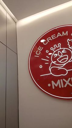 the ice cream shop sign is red and white with an image of a cartoon character on it