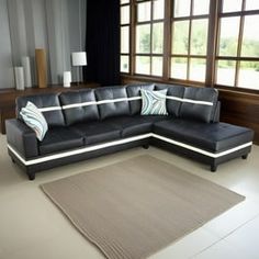 a living room with a large black sectional couch and rug on the floor in front of windows