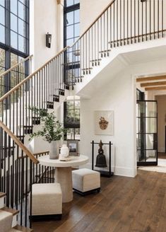 a staircase in a home with white walls and wood flooring next to a table