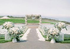 an outdoor ceremony set up with white flowers and greenery