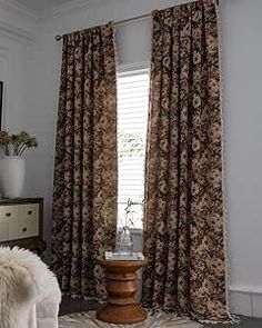 a bed room with a neatly made bed and two large window covered in brown curtains