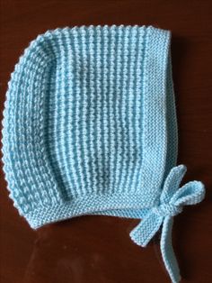 a blue and white knitted hat with a bow on the side sitting on a table